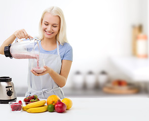 Image showing smiling woman with blender and fruit milk shake