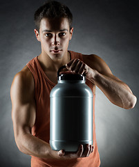 Image showing young male bodybuilder holding jar with protein