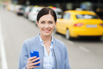 Image showing smiling woman with smartphone over taxi in city