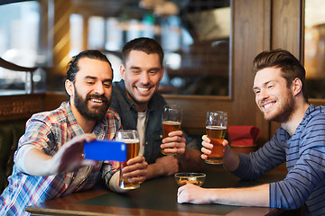 Image showing male friends with smartphone drinking beer at bar