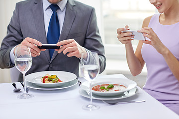 Image showing close up of couple with smartphones at restaurant