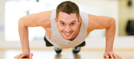 Image showing smiling man doing push-ups in the gym