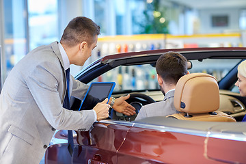 Image showing happy couple with car dealer in auto show or salon