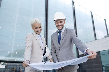 Image showing smiling businessmen with blueprint and helmets