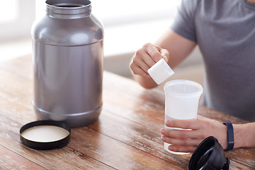 Image showing close up of man with protein shake bottle and jar