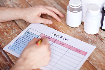 Image showing close up of man with protein jars and diet plan