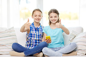 Image showing happy girls with smartphone sitting on sofa