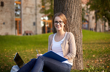 Image showing happy student girl writing to notebook at campus