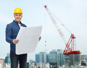 Image showing smiling male builder in helmet with blueprint