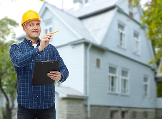 Image showing smiling male builder in helmet with clipboard