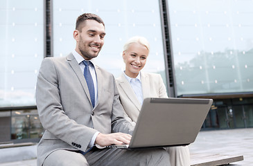 Image showing smiling businesspeople with laptop outdoors