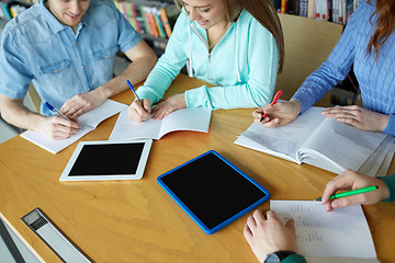 Image showing happy students writing to notebooks in library