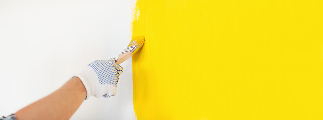 Image showing close up of male in gloves painting a wall
