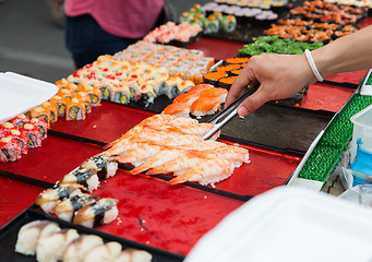 Image showing close up of hand with tongs taking sushi