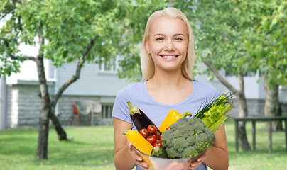 Image showing smiling young woman with vegetables in home garden