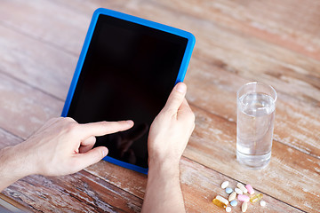 Image showing close up of hands with tablet pc, pills and water