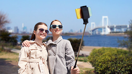 Image showing happy girls with smartphone selfie stick in tokyo