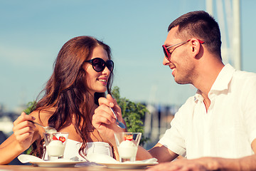 Image showing smiling couple eating dessert at cafe