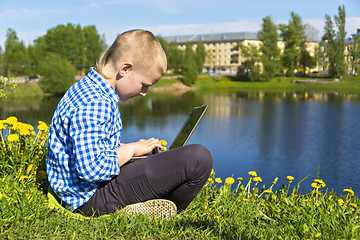 Image showing Ten year boy with laptop on riverside