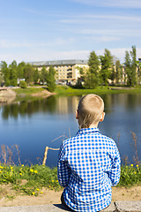 Image showing Ten year boy looks on city from river shore