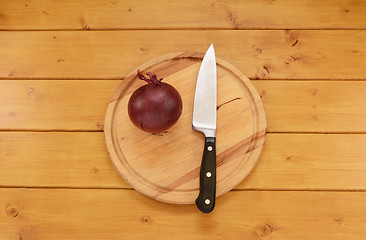 Image showing Red onion with a knife on a chopping board