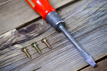 Image showing screws and old screwdriver with a red wooden handle