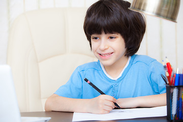 Image showing smiling child doing homework with computer