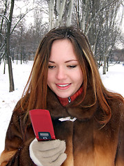 Image showing The girl in the winter in park with phone in a hand