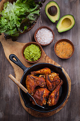 Image showing Grilled chicken legs and wings with guacamole