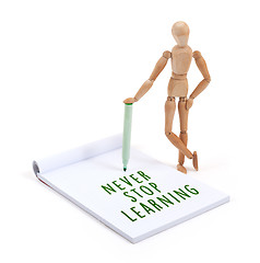 Image showing Wooden mannequin writing in scrapbook - Never stop learning