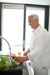 Image showing man cooking at home preparing salad in kitchen