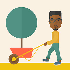 Image showing Young african man pushing the cart with tree.