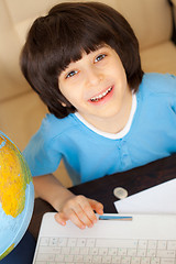 Image showing smiling boy doing homework on computer