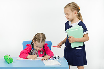 Image showing Girl teacher stands at the student desk