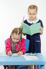 Image showing Teacher standing behind the pupil looks notebook