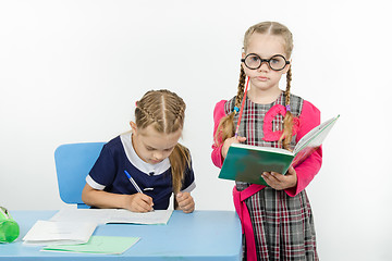 Image showing The student writes in a notebook under supervision of teacher