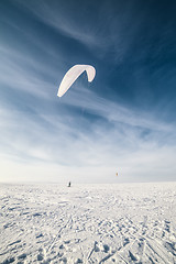 Image showing Kiteboarder with blue kite on the snow