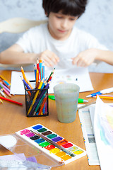 Image showing palette with paints, crayons and young artist