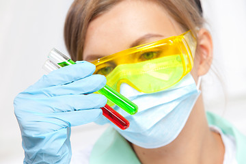 Image showing doctor in a mask examines test tubes