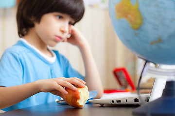 Image showing boy sitting with a laptop and eating apple