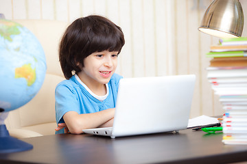 Image showing smiling boy looking at a computer monitor