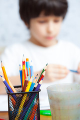 Image showing colored pencils for drawing in pencil holders and the child on b