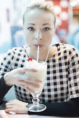 Image showing Woman drinking milk shake in diner.