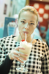 Image showing Woman drinking milk shake in diner.