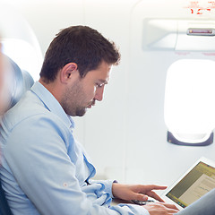 Image showing Businessman working with laptop on airplane.