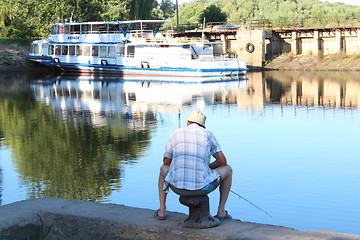 Image showing fisherman sitting and fishing in the city river