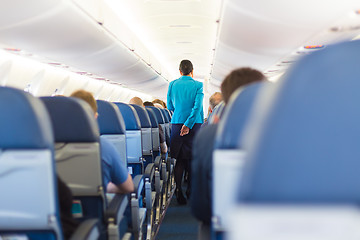 Image showing Interior of airplane with stewardess walking the aisle.