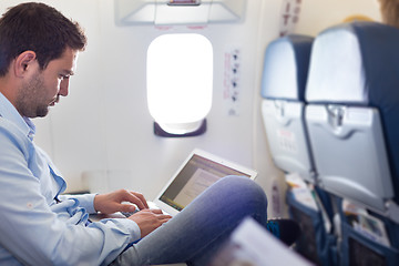 Image showing Businessman working with laptop on airplane.