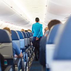 Image showing Interior of airplane with stewardess walking the aisle.