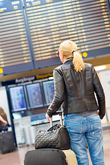 Image showing Female traveller checking flight departures board.